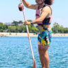 Person on SUP board with beer strapped to paddle