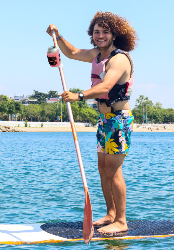 Person on SUP board with beer strapped to paddle